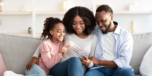 Family sits on couch and views their vacation booking confirmation